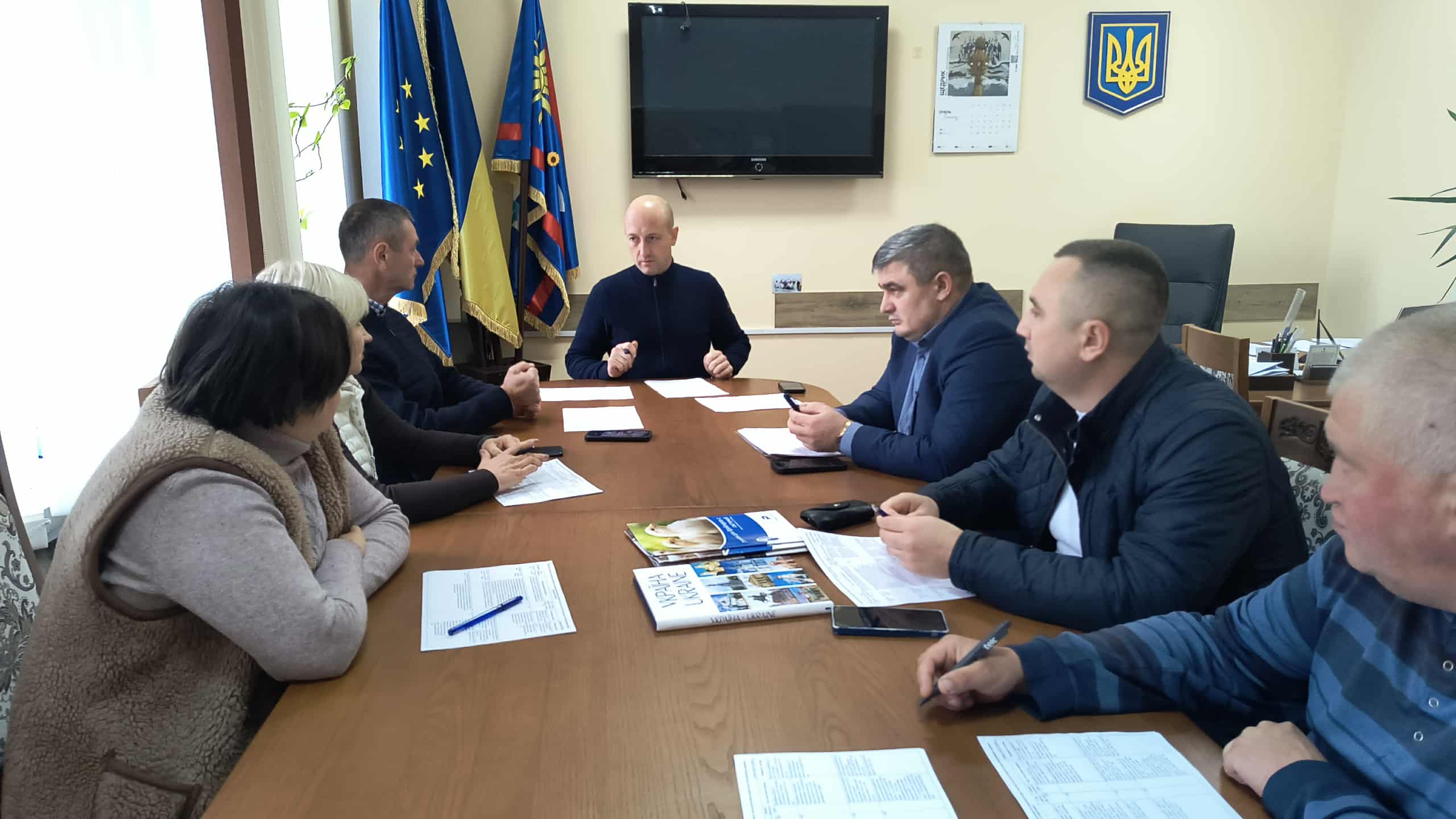 В кабінеті за робочим  столом сидят члени Комісії, перед ними документи та записники