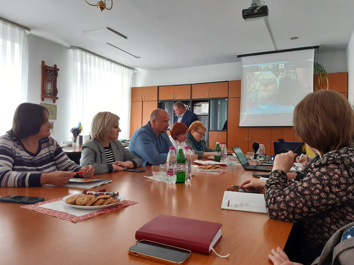 Учасники робочої групи в кабінеті сидят за робочим столом та дивляться на екран для проектора