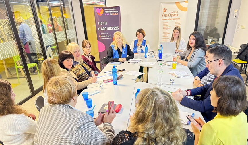 Учасники заходу сидять за круглим столом в аудиторії