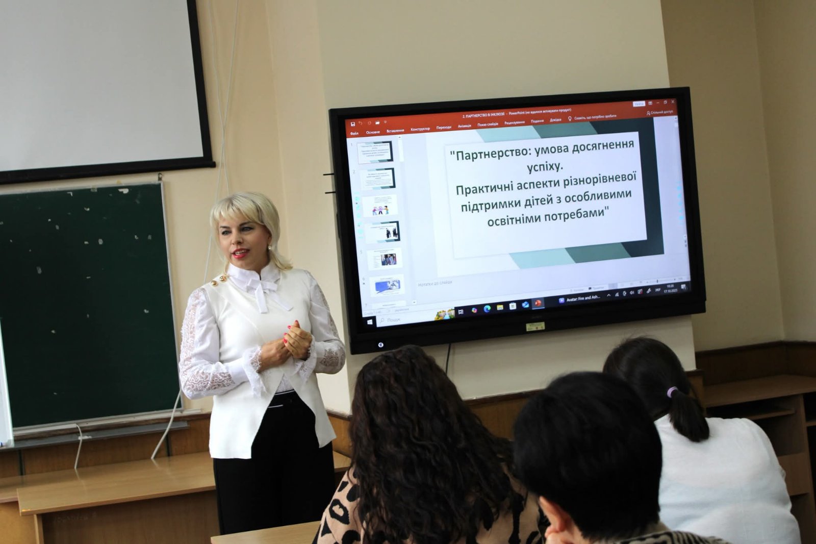 Фахівець представляє матеріал аудиторії; позаду спікера видно презентацію.