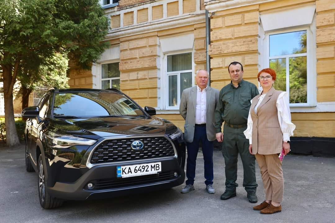 Три людини стоять біля автомобіля.