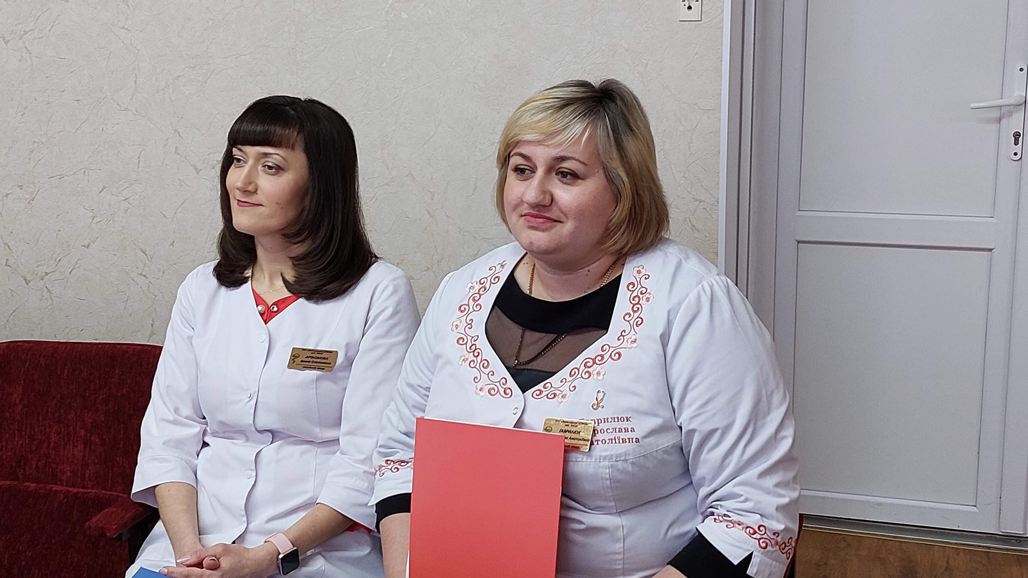 Дві жінки в білих халатах сидять на дивані.