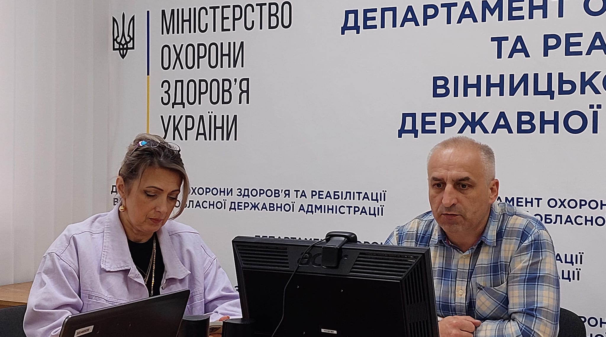 Двоє людей сидять за столом з ноутбуком.