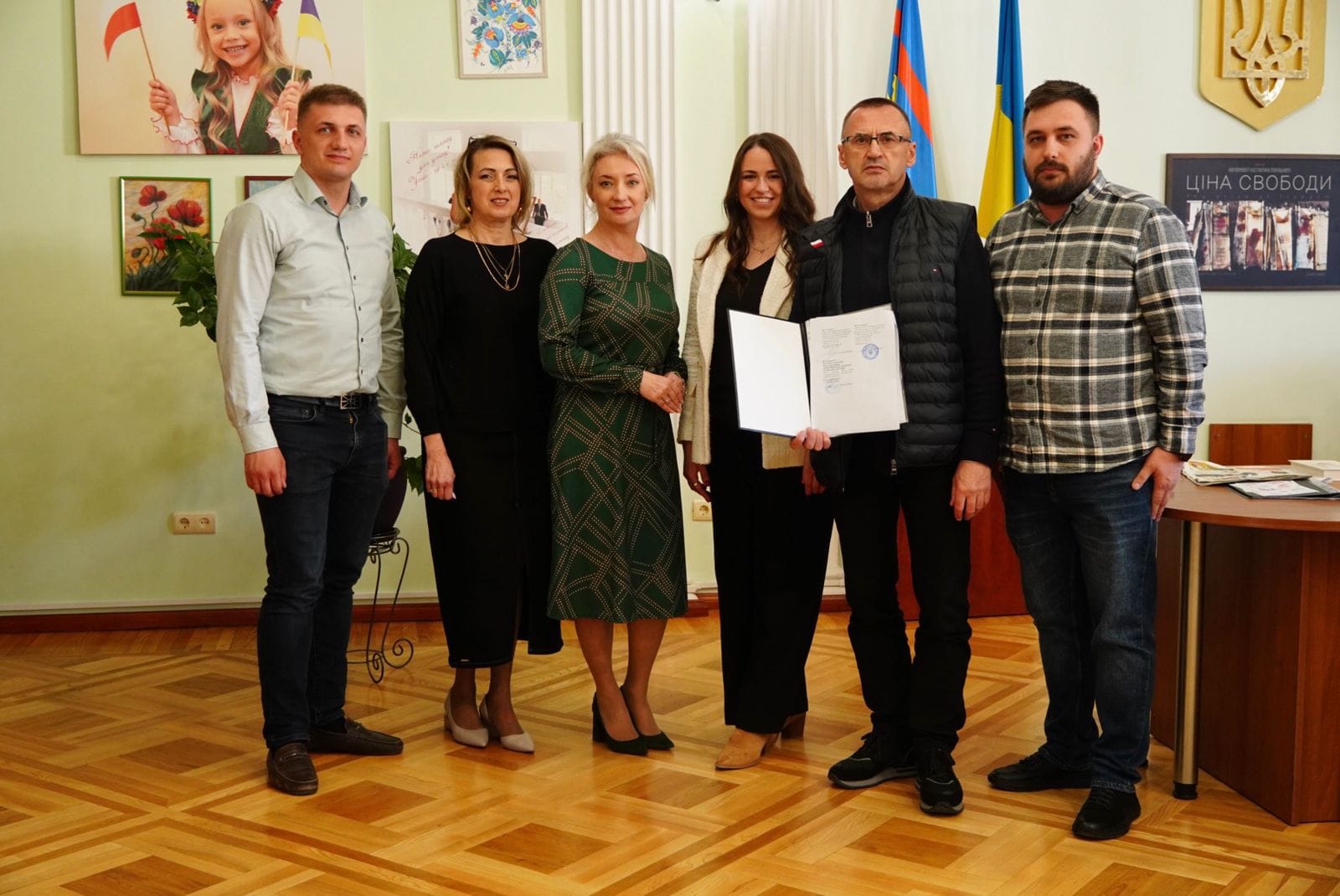 Група людей у кімнаті тримає папери.