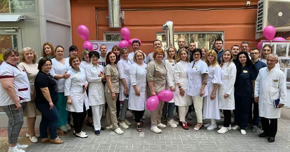 Група людей у білих халатах з рожевими кульками.