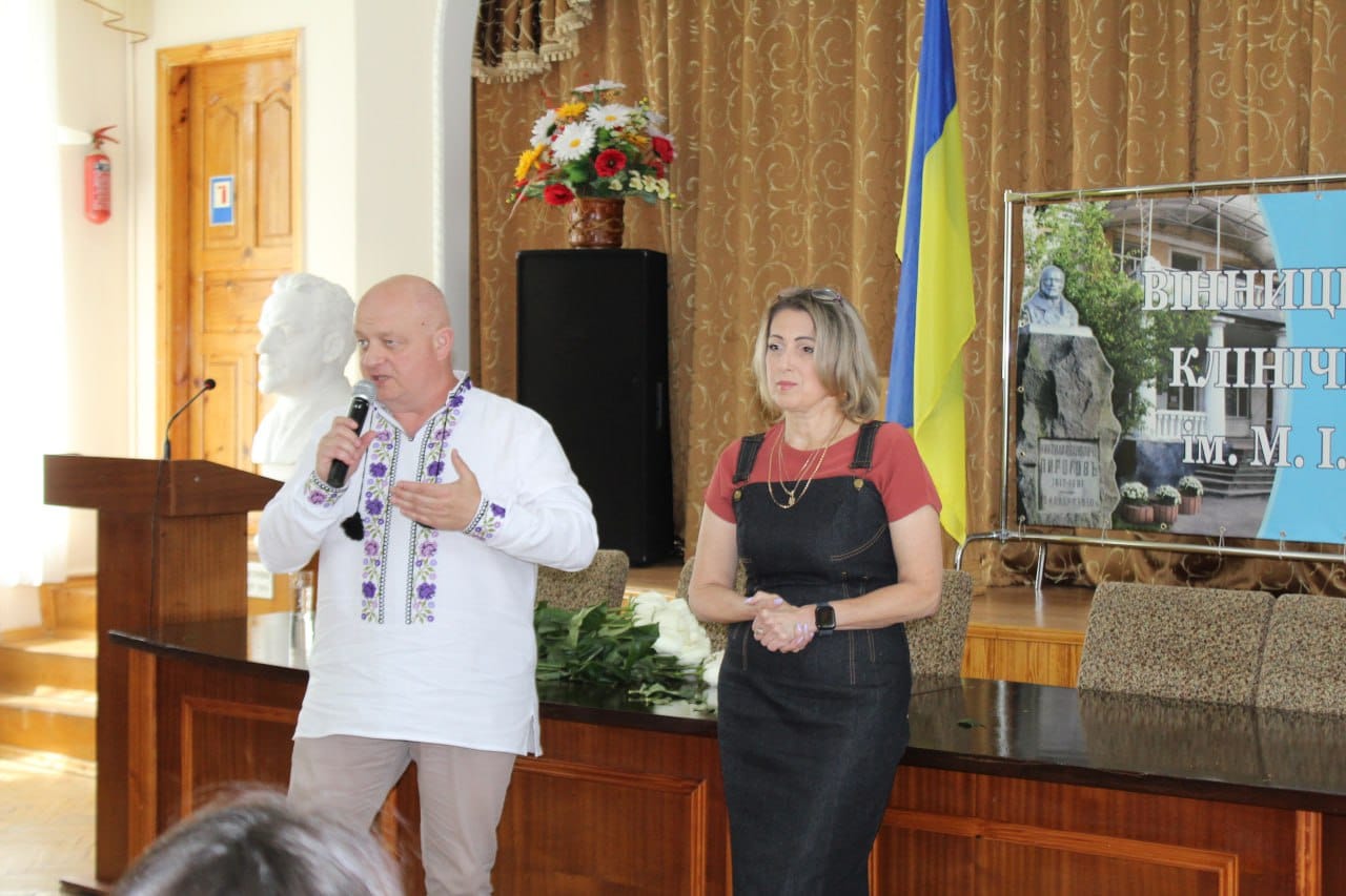 Чоловік і жінка стоять перед трибуною.