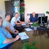 Учасники наради сидять в кабінеті за робочим столом перед ними монітор ком'ютера