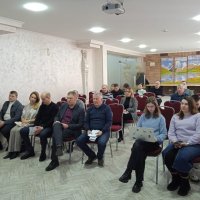 Учасники заходу сидят на стільцях у залі де проходить захід