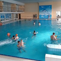 Діти з батьками плавають і граються в басейні